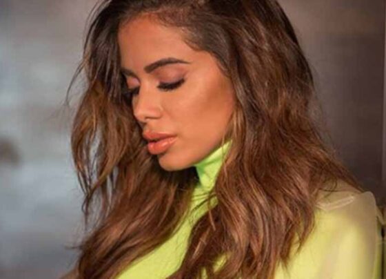 Anitta triste de camisa verde de gola alta
