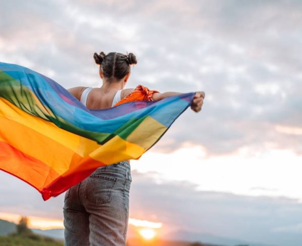 Foto colorida de mulher com bandeira do orgulho LGBT